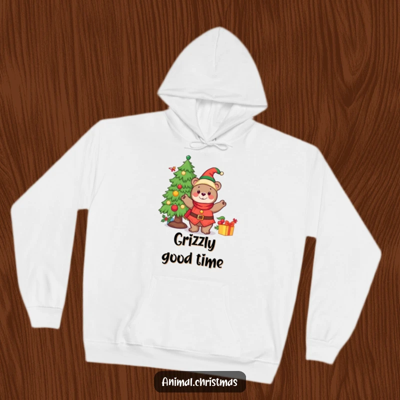 Funny hoodie depicting a cheerful bear dressed as an elf, actively decorating a Christmas tree with ornaments.